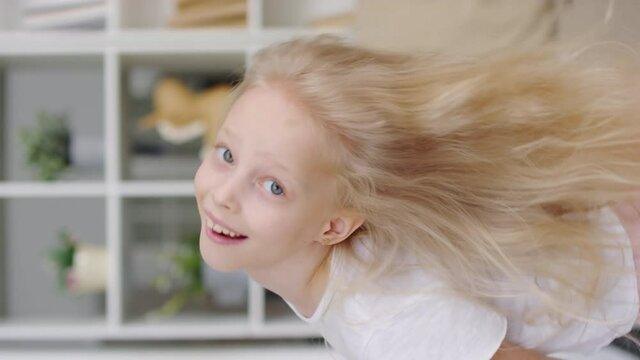 Vertical format video of adorable little girl with blond hair laughing and turning while looking at camera