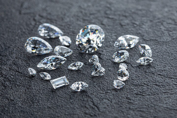 Polished diamonds of various shapes and sizes at workplace of jewelry expert evaluating the quality...