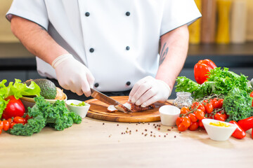 Young chef is cutting octopus in a modern kitchen. The man prepares food at home. Cooking healthy and tasty food.