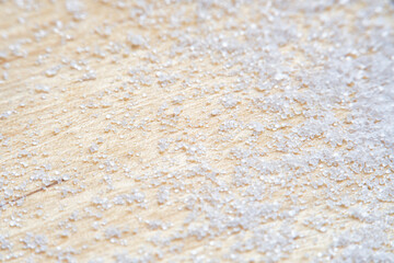 Background with salt scattered on a wooden surface. Close-up of blurry salt granules in soft focus...