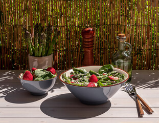 Fresh strawberry, green asparagus, feta cheese, baby spinach, and arugula salad served in a bowl