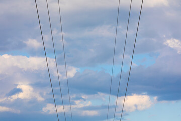 Seis (6) lineas electricas (cables) sobre un cielo azúl con nubes