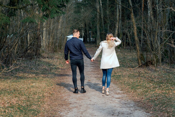Fototapeta premium Beautiful loving couple going for a walk in a forest in the spring,autumn outdoors sunny day.Rear view.