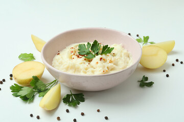 Plate of mashed potatoes and ingredients on white background
