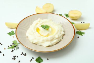 Plate of mashed potatoes and ingredients on white background