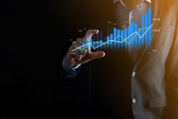 Business man holding and showing holographic graphs and stock market statistics gain profits. Concept of growth planning and business strategy. Display of good economy form digital screen.