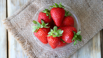 Fresh ripe strawberries in a plastic bowl. Large strawberries.