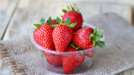 Fresh ripe strawberries in a plastic bowl. Large strawberries.