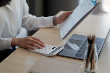 Close up a woman working about financial with calculator at her office to calculate expenses,...