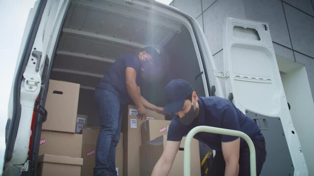 Video of two couriers in protective masks unloading packages. Shot with RED helium camera in 8K.