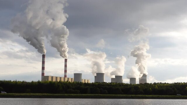 A stable view of a coal-fired power plant with smoking chimneys. The shot was taken in soft, natural light.