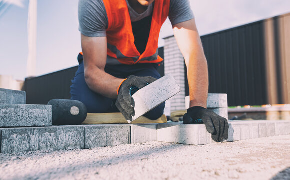 Worker lining paving slabs path