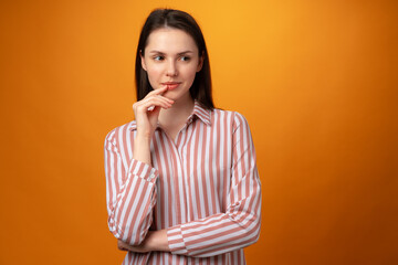 Studio portrait of beautiful young woman thinking against yellow background