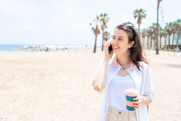 girl drinking coffee on the beach calling on the phone