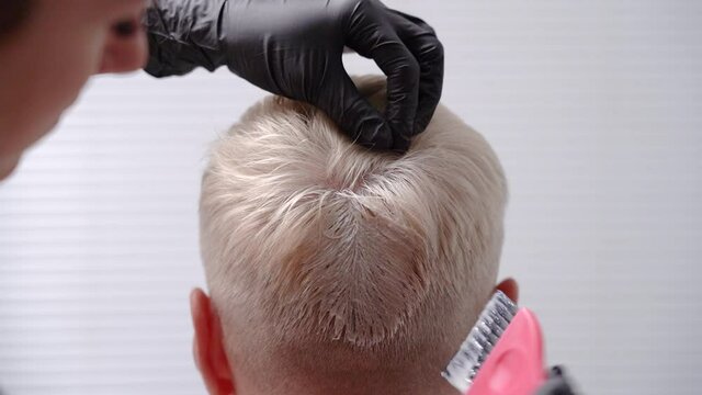 Applying paint on the blond men's hair on the head. Hair dyeing. High quality FullHD footage