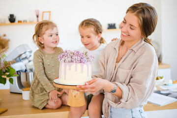 Mom and daughter are baking a beautiful dessert with cream.