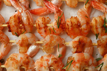 Obraz na płótnie Canvas Tasty grilled shrimp skewers on baking paper, close up