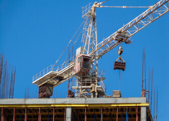 Building under construction. Kazakhstan (Ust-Kamenogorsk). Residential building. Urban grunge. New residential area. Construction site. Construction crane. Blue sky