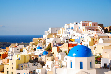 Fototapeta premium Scenic view of the white residential houses and church with blue dome. Oia, Santorini, Greece