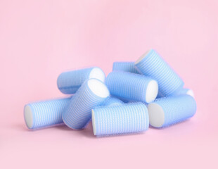 Fototapeta na wymiar Many light blue hair curlers on pink background