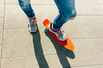 Young guy in ripped jeans standing with penny board in the park. summer activities skateboarding
