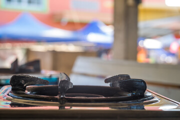 A traditional Thai gas stove with a rustic metal burner sits prominently in the foreground, its...