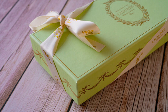 Nice, France - 18.06.2021: Famous French Macaroons from Laduree store. A green special gift box on a wooden background. Assorted Laduree Macaroons in the gift box. High quality photo