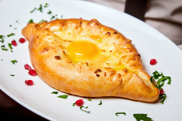 Ajarian traditional flatbread khachapuri or hachapuri with cheese, egg and butter on a plate