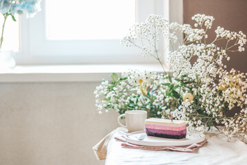 Raspberry cake on a nordic plate in a bright room decorated with seasonal flowers