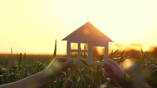 A happy family holds a model house at sunset. Construction concept, family home, home loan, dream of a home