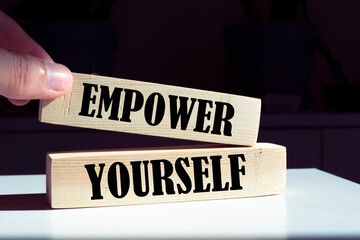 Empower yourself symbol. Wooden blocks with words 'Empower yourself' on beautiful orange background. Businessman hand. 