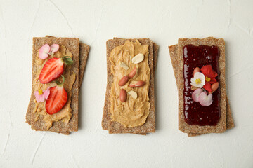 Fresh rye crispbreads with different toppings on white table, flat lay