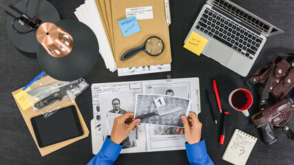 The FBI agent examines the criminal case, photographs and evidence. Top view