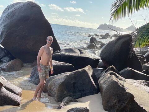 Jeune homme en maillot devant des rochers sur la plage