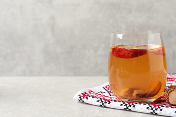 Delicious compote with dried apple slices in glass and rushnyk on light grey table, space for text