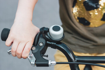 Child's hand on a bicycle handlebar. Bike bell. A child's hand holds a bicycle brake. Cycling trip. Bicycling. Braking.