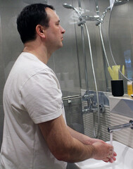 A man washes his hands with water in the bathroom sink. The concept of an attentive attitude to cleanliness and one's health. The importance of hygiene in the context of the coronavirus pandemic.