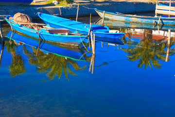 Fototapeta na wymiar Greece, Beautifull reflections of wooden fishing boats on water on sea lake in Aitoliko in Central Greece