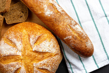 Freshly baked bread on the table. White round bread and French baguette on the kitchen table. Bakery pastries. Crispy bread. Loaf of bread.