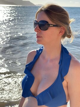Jeune femme en biniki bleu de profil devant la mer 