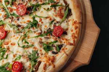 Italian food. Classic pizza with large sides, mushrooms, cherry tomatoes, arugula, parmesan cheese on wooden board