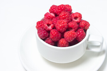 Raspberries in a cup on a white background. Red ripe raspberries close-up. Delicious berry