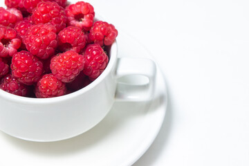 Raspberries in a cup on a white background. Red ripe raspberries close-up. Delicious berry
