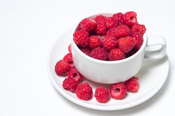 Raspberries in a cup on a white background. Red ripe raspberries close-up. Delicious berry