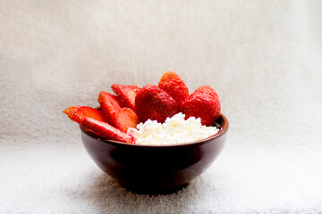 Cottage cheese with strawberries in a small brown piala on a white background