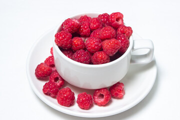 Raspberries in a cup on a white background. Red ripe raspberries close-up. Delicious berry