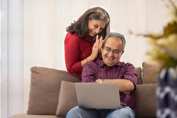 A HAPPY COUPLE SITTING TOGETHER AND USING LAPTOP FOR VIDEO CALLING