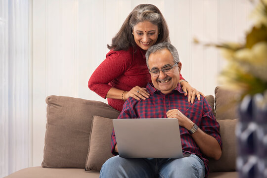 A HUSBAND AND WIFE HAPPILY USING LAPTOP FOR VIDEO CALLING - Powered by Adobe