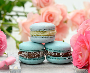 stack of blue macarons on a white table and pink rosebuds