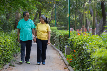 A SENIOR COUPLE WALKING HAND IN HAND IN A PARK